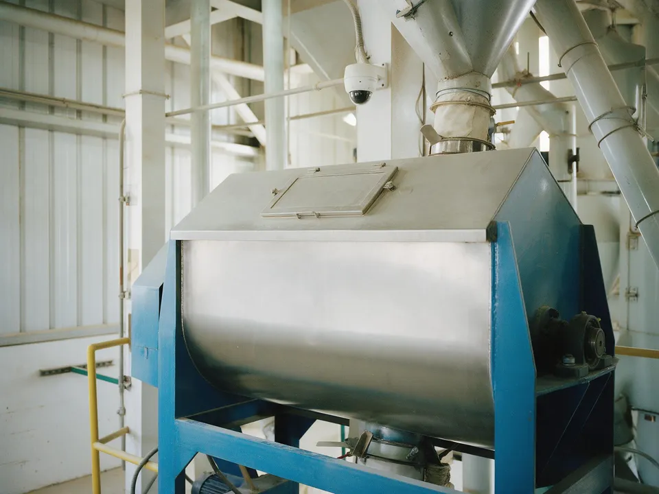 A ribbon mixer on a blue steel frame inside a feed mill
